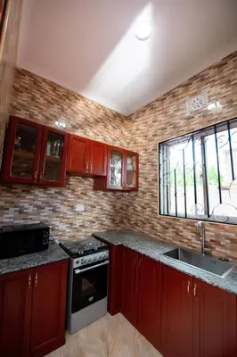 a kitchen with red cabinets and a stove and windows at Private Nest Apartment 2 in Nkoanrua