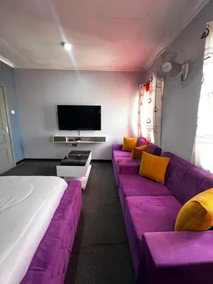 a living room with a purple couch and a tv at Hadraj Sokokuu Apartment1 in Arusha