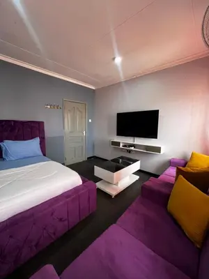 a bedroom with a purple bed and a flat screen tv at Hadraj Sokokuu Apartment1 in Arusha