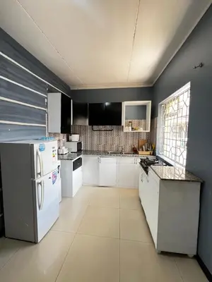 a kitchen with white appliances and a blue wall at Hadraj Sokokuu Apartment1 in Arusha
