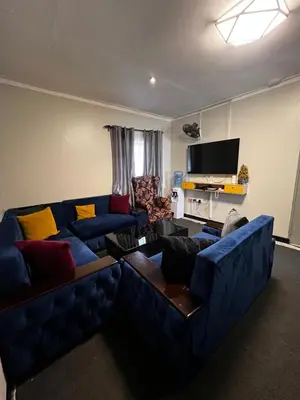 a living room with a blue couch and a television at Hadraj Sokokuu Apartment3 in Arusha