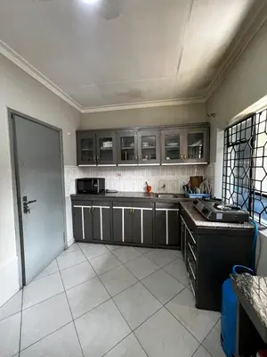 a kitchen with gray cabinets and a white tile floor at Hadraj Sokokuu Apartment3 in Arusha
