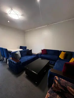a living room with blue couches and a table at Hadraj Sokokuu Apartment3 in Arusha