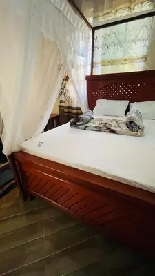 a wooden bed with white sheets and a canopy at R Kelly Tanzania in Arusha