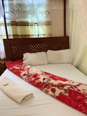 a bed with a red and white blanket on it at R Kelly Tanzania in Arusha