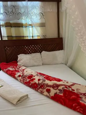 a bed with a red and white blanket on it at R Kelly Tanzania in Arusha