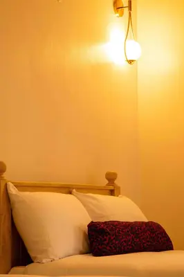 a bed with a white pillow and a light above it at The Hidden Valley Lodge in Arusha