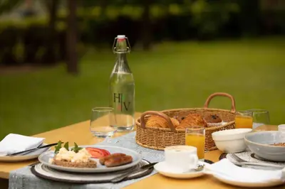 a picnic table with a basket of bread and a bottle at The Hidden Valley Lodge in Arusha