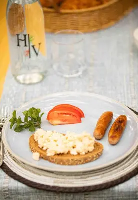 a plate of food with sausage and tomatoes on a table at The Hidden Valley Lodge in Arusha