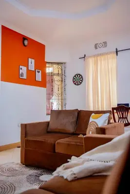a living room with a brown couch and an orange wall at Earth Villas in Arusha