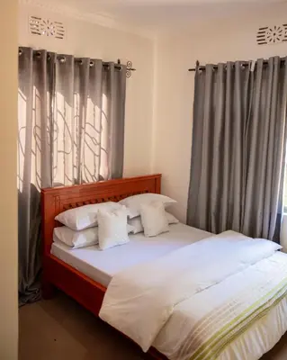 a bedroom with a large bed with gray curtains at Earth Villas in Arusha