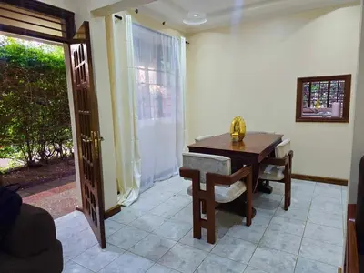 a dining room with a wooden table and a door at A private bedroom in a shared home in Arusha in Arusha