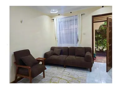 a living room with a couch and a chair at A private bedroom in a shared home in Arusha in Arusha