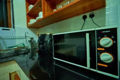 a microwave on a wall in a kitchen at Favourites home-English breakfast in Arusha
