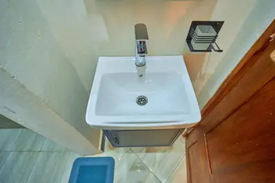 a white sink in a small bathroom next to a door at Favourites home-English breakfast in Arusha
