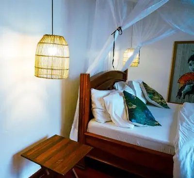 a bedroom with a bed with a lamp and a table at Garden Villa Homestay in Arusha