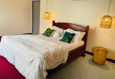 a bedroom with a bed with white sheets and pillows at Garden Villa Homestay in Arusha