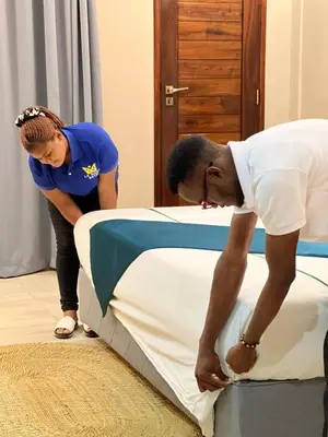 a man and a woman standing next to a bed at La Mama Hotel in Uru