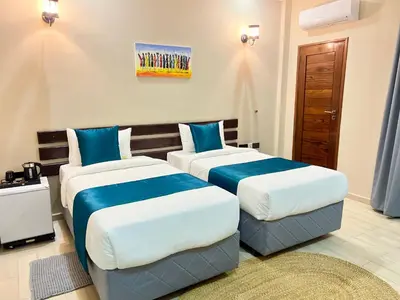 two beds in a room with blue and white at La Mama Hotel in Uru