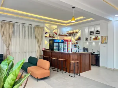a bar in a restaurant with a counter and chairs at La Mama Hotel in Uru