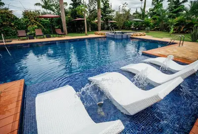 a pool with two white chairs and a table at La Mama Hotel in Uru