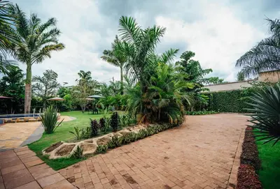 a courtyard with palm trees and a brick walkway at La Mama Hotel in Uru