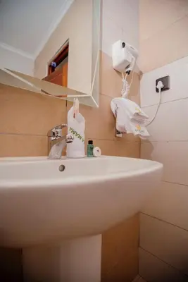 a bathroom with a white sink and a mirror at La Mama Hotel in Uru