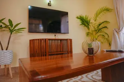 a wooden table with a television and two plants at Kwetu Arusha Villa in Arusha