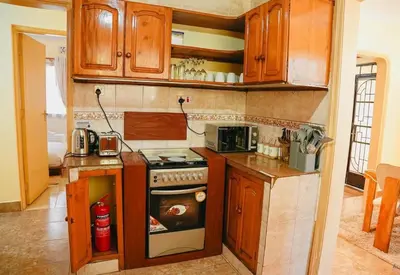 a kitchen with wooden cabinets and a stove at Kwetu Arusha Villa in Arusha