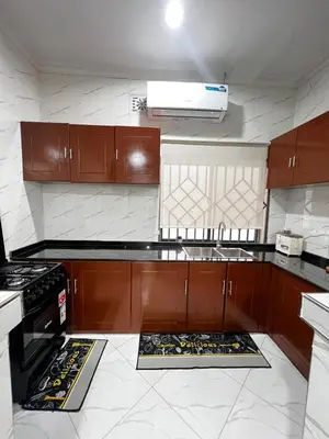 a kitchen with wooden cabinets and a stove top oven at Hadraj Sokoine Apartment1 in Arusha