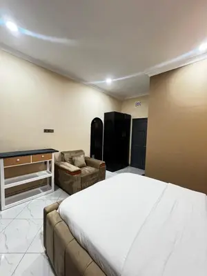 a bedroom with a bed and a couch and a table at Hadraj Sokoine Apartment2 in Arusha
