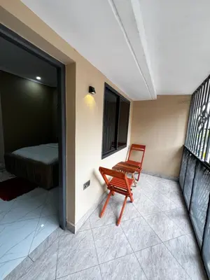 a red chair sitting in a room with a bed at Hadraj Sokoine Apartment2 in Arusha