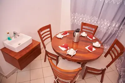 a wooden table with chairs and a sink in a kitchen at Villa Malkia's in Enaboishu