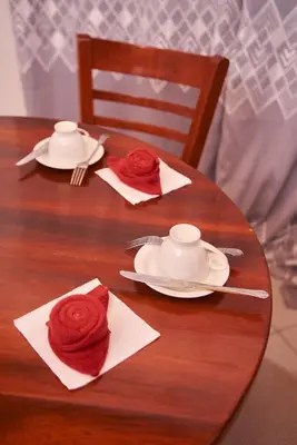 a wooden table with red roses on top of it at Villa Malkia's in Enaboishu