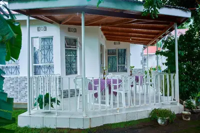 a porch with chairs and tables in front of a house at Villa Malkia's in Enaboishu