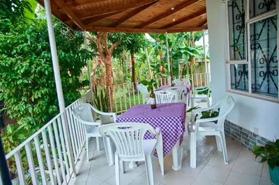 a porch with white chairs and a table and a tree at Villa Malkia's in Enaboishu