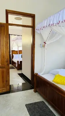 a bedroom with a bed and a door with a mirror at African Jacana Inn and Camps in Mto wa Mbu