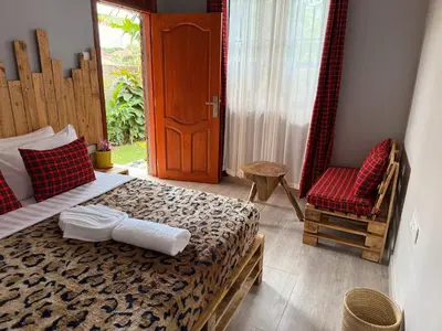 a bedroom with a bed and a chair and a door at Baraka Home in Arusha