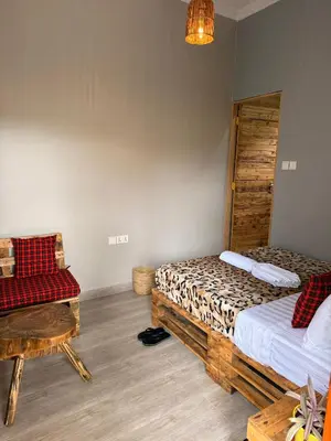 a room with two beds and a chair in it at Baraka Home in Arusha