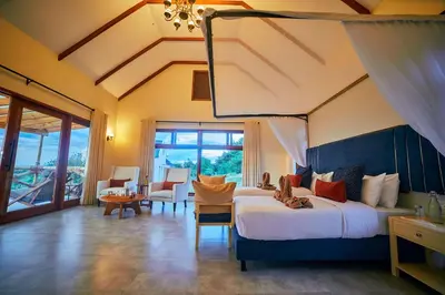 a bedroom with a large bed and a living room at Tarangire Luxury Hideaway in Mbesi