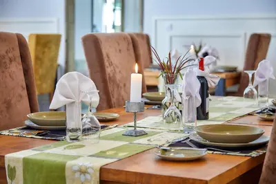 a dining room table with a candle and plates and chairs at Pamoja Farm Villas in Karatu