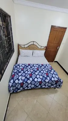 a bedroom with a bed with a floral comforter at Milele Homestay in Boma la Ngombe