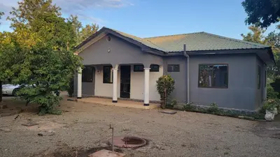 a small white house with a driveway at Milele Homestay in Boma la Ngombe
