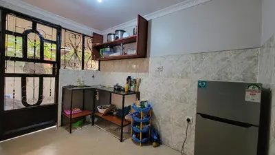 a kitchen with a refrigerator and a counter and a window at Milele Homestay in Boma la Ngombe
