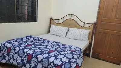 a bedroom with a bed with a blue and white comforter at Milele Homestay in Boma la Ngombe