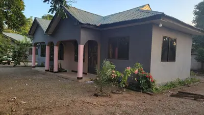 a blue and white house with flowers in front of it at Milele Homestay in Boma la Ngombe