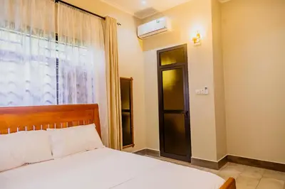 a bedroom with a bed and a window with a air conditioner at Dodo homes in Uru