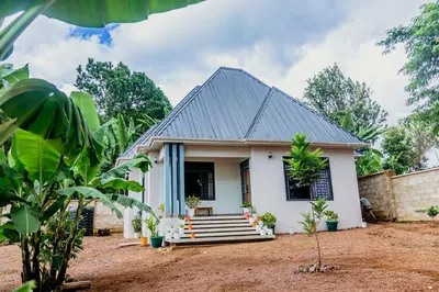 a small white house with a grey roof at Dodo homes in Uru
