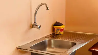 a stainless steel sink in a kitchen with a trash can at Safari Roots Hostel in Arusha