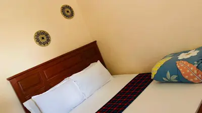 a bed with a wooden headboard and two pillows at Safari Roots Hostel in Arusha